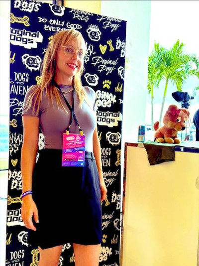 Leah Bluewater at a blockchain conference, standing in front of a Doginal Dogs backdrop